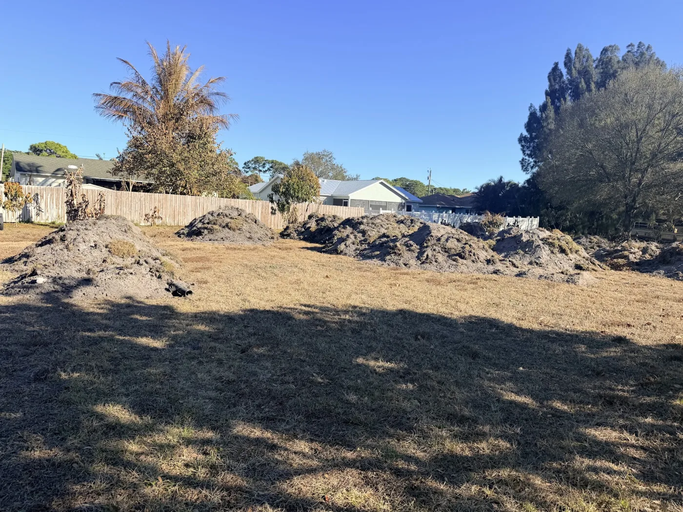 Lot mid-clearing with brush piles ready to process
