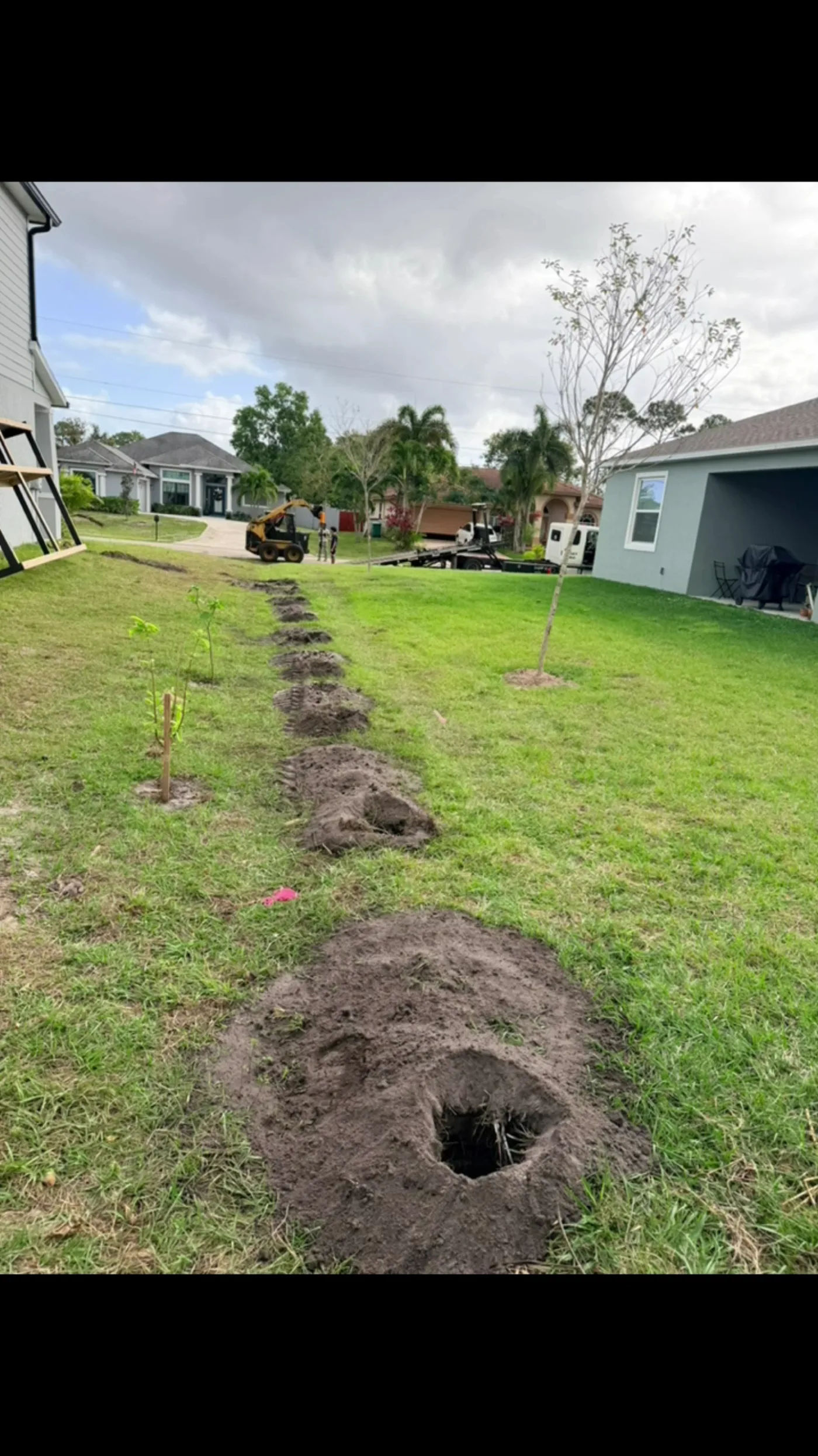 Augered post hole and marked trench line in a lawn